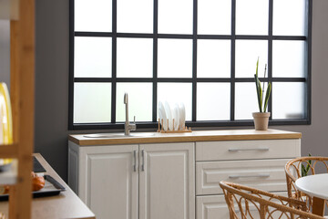 Interior of modern kitchen with white counters and sink