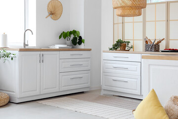 Interior of light kitchen with white counters near window