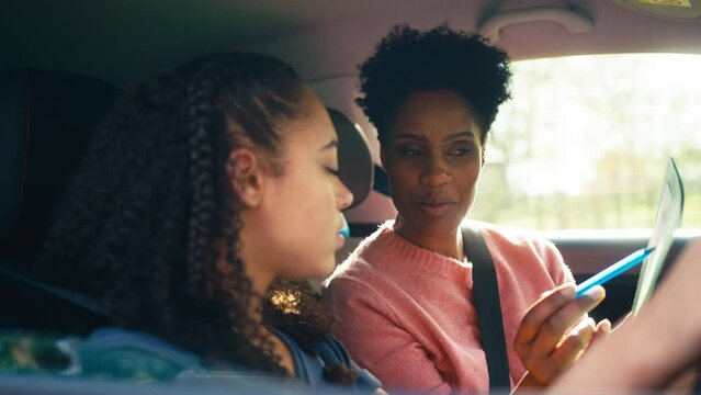 Teenage girl in car having driving lesson from female instructor or parent- shot in slow motion