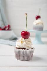 Tasty cherry cupcakes on table