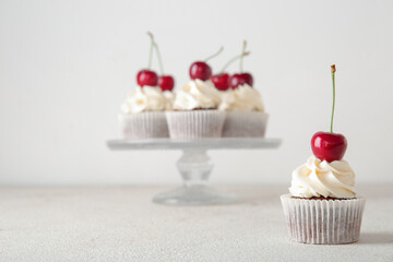 Tasty cherry cupcake on light background