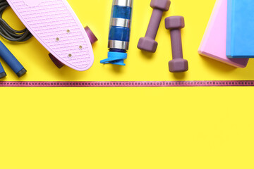 Composition with different sports equipment and measuring tape on yellow background