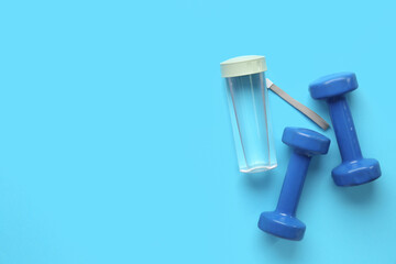 Bottle of water and dumbbells on color background
