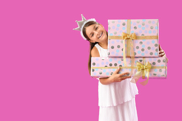 Happy little girl with Birthday gift boxes on purple background