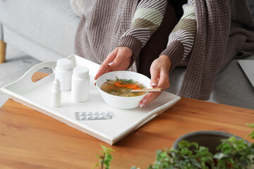 Ill young woman with chicken soup at home, closeup
