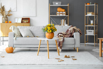 Interior of light living room with autumn bouquet and sofa