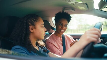 Teenage girl in car having driving lesson from female instructor or parent- shot in slow motion