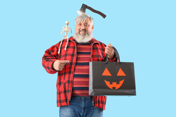 Mature man dressed for Halloween with gift bag on blue background