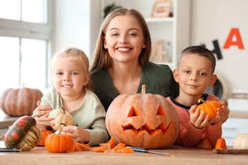 Happy mother with her little children and Halloween pumpkins in kitchen