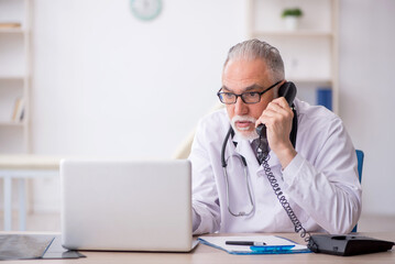 Fototapeta premium Old male doctor in telemedicine concept