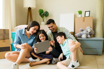 Happy parents with children moving to a new apartment using a tablet