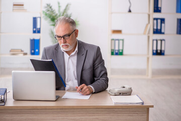Fototapeta premium Old male employee working in the office