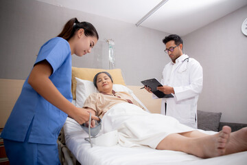 Obraz premium Doctor checkup and diagnostic while nurse measuring blood pressure with patient elderly at hospital ward, physician diagnosis disease of patient and care in clinic, medical and insurance concept.