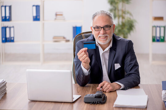 Old male employee holding credit card