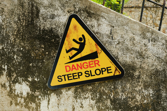 A picture of warning sign of danger steep slope at the wall.