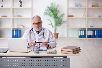 Old male doctor working in the clinic