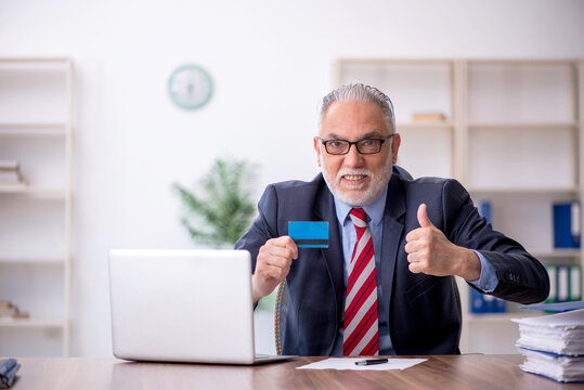 Old male employee holding credit card