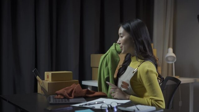 Asian woman checks clothing stock and online retail business, sells clothes on internet sales website, live streams 4K video, fashion discusses and sells clothes in online store.