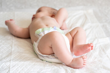 Fototapeta na wymiar Diapered infant laying with feet in focus. Concept of cherishing small moments in life