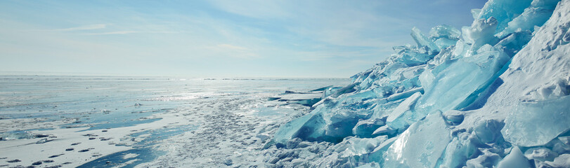 Huge blocks of transparent blue ice, hummocks on the frozen Lake Baikal. Winter landscape, panorama