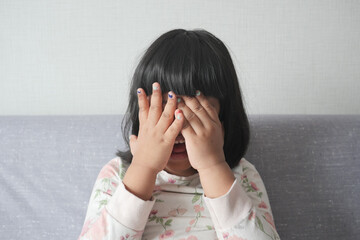 a upset child girl cover her face with hand 