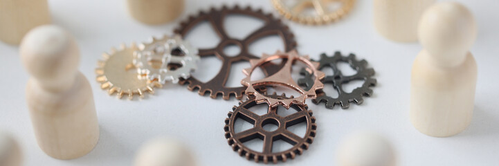 Wooden figures of people with metal gears close up.