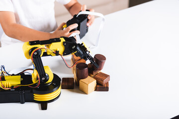 Happy Asian little kid boy using remote control playing robotic machine arm for pick up wood block, Funny child learning successful getting lesson control robot arm, Technology science education