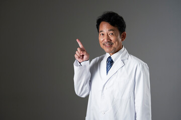 左側を指差す中年の医師　黒背景