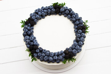 Delicious berry cake with fresh blackberry and  blueberry ,  top view , white  wooden board