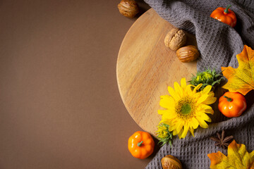 Autumn Thanksgiving board. Sunflower, pumpkins, yellow leaves, nuts, brown background. Autumn template