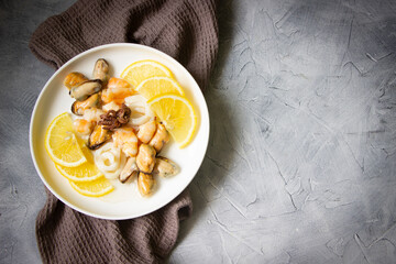 Seafood with fresh  lemons-shrimps, mussels, squid, baby octopus, white plate, gray background....