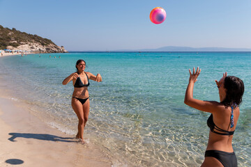 Summer vacation, sport and people concept - young happy people have fun and play beach volleyball with volleyball ball on beach