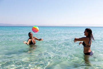 Summer vacation, sport and people concept - young happy people have fun and play beach volleyball with volleyball ball on beach