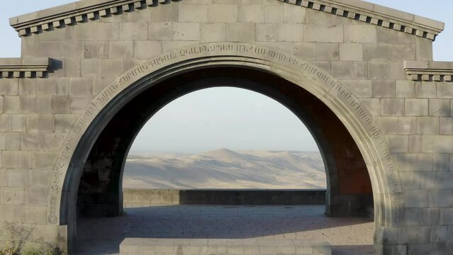 Forward reveal aerial shot of Charents Arch on sunny morning. Voghjaberd, Armenia.