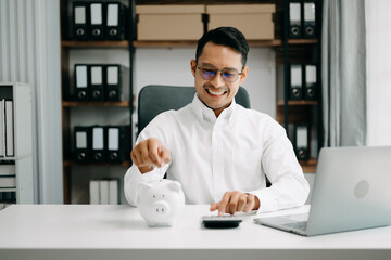 Asian Man are putting coins in a piggy bank for a business that grows for profit and saving money for the future. planning for retirement concept