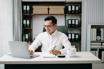 Asian Man are putting coins in a piggy bank for a business that grows for profit and saving money for the future. planning for retirement concept