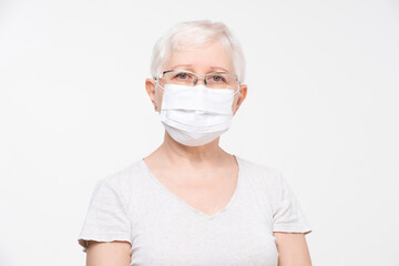 Headshot portrait of elderly Caucasian woman wearing medical face mask in isolated white background studio shot