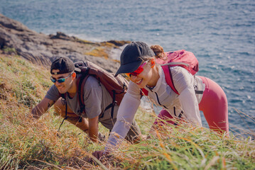 Happy young couple climbs to the top in the mountains near the ocean