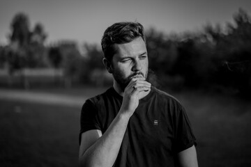 Black and white photo of a man smoking electrical vape cigarette looking cool