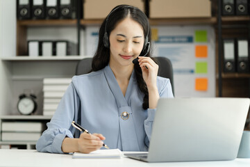 Serious call center operator in wireless headset talking to customer, woman in headphones with microphone consulting customer on phone in customer support service, looking at computer screen.