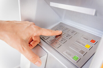 Young woman using the card for withdrawing the cash in the ATM