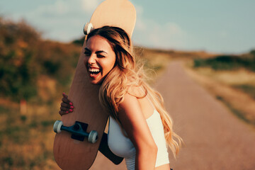 Young woman laughing and holding skate at street outside of city