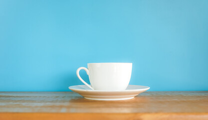 White coffee cup on wooden desk with blue background