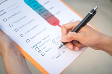 Action of a chemical engineer is using the pen to checking on oil refinery distillation process inspection form. Industrial working scene,close-up and selective focus.