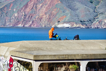 Woman in Orange Coat Overlooking the Ocean