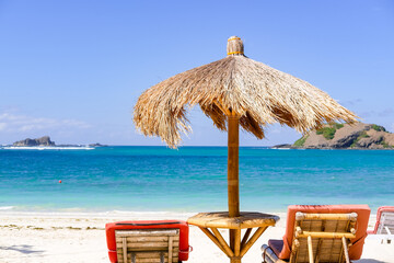Beachside lounge chairs and umbrellas to relax and enjoy the beauty of the beach, Umbrellas made from palm leaves and wood, and sun shade ropes provide a shady getaway on Lombok Beach