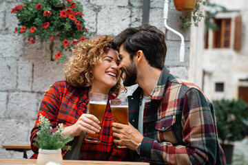 Young smiling tourist couple drinking beer in the city. Two happy attractive people bonding on their first romantic trip together. Man and woman celebrating with alcoholic drink, having a toast.