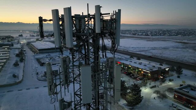 5G cell tower winter evening. Close-up drone footage of a cell phone tower antenna array at dusk.