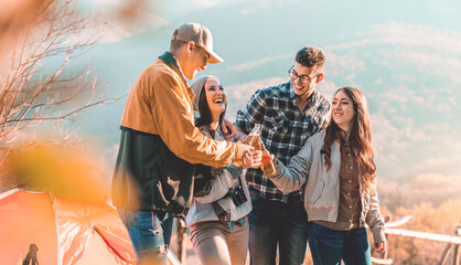 Happy group of four friends toasting beer bottles on a beautiful autumn day and having a great time...