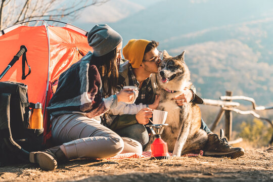Young couple and their dog camping in the mountains on a beautiful autumn day spending time outdoors and appreciating nature.